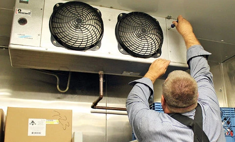A man is working on a refrigerator in a kitchen.