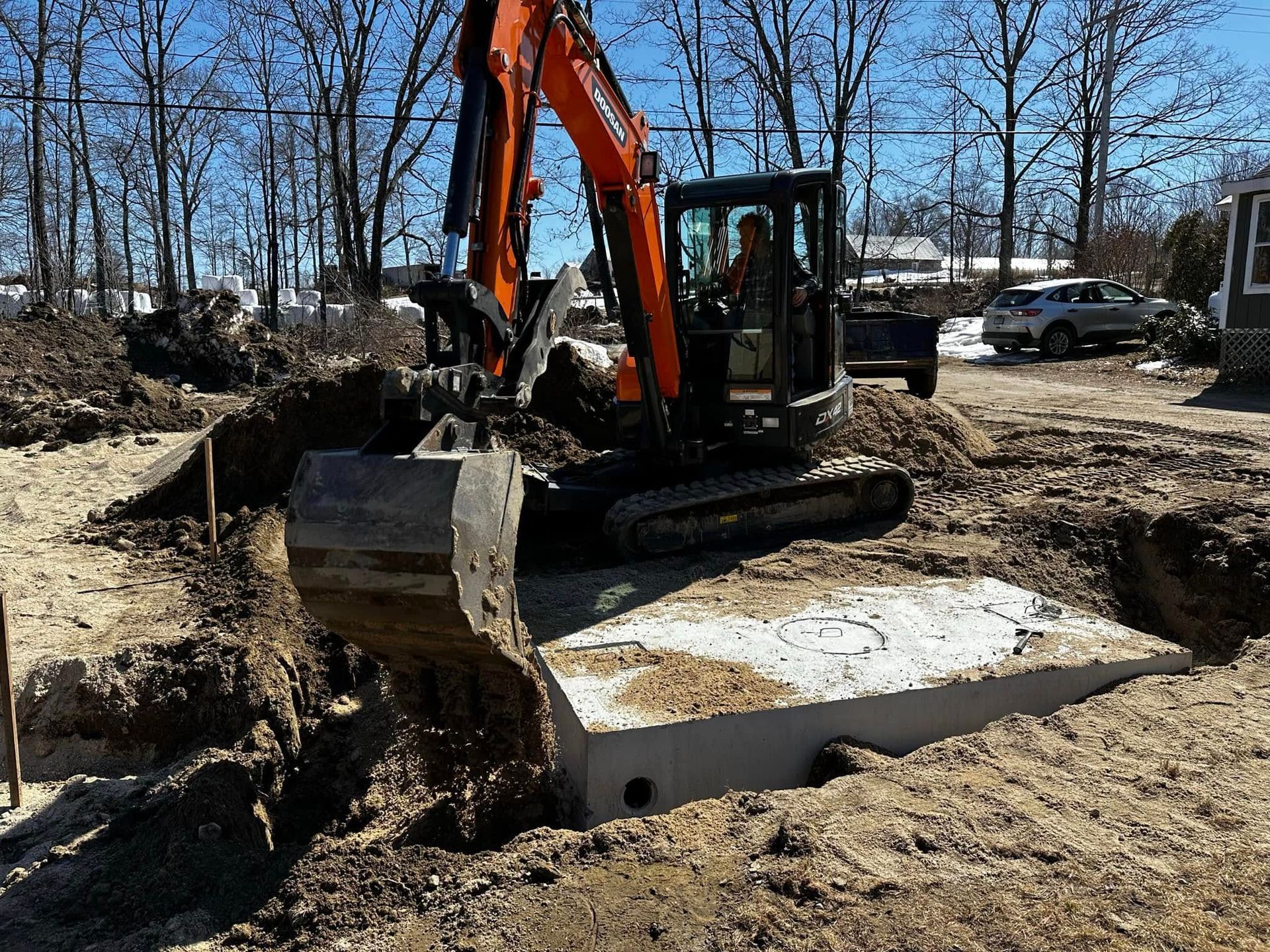An excavator digging around a concrete structure in a construction site on a sunny day.