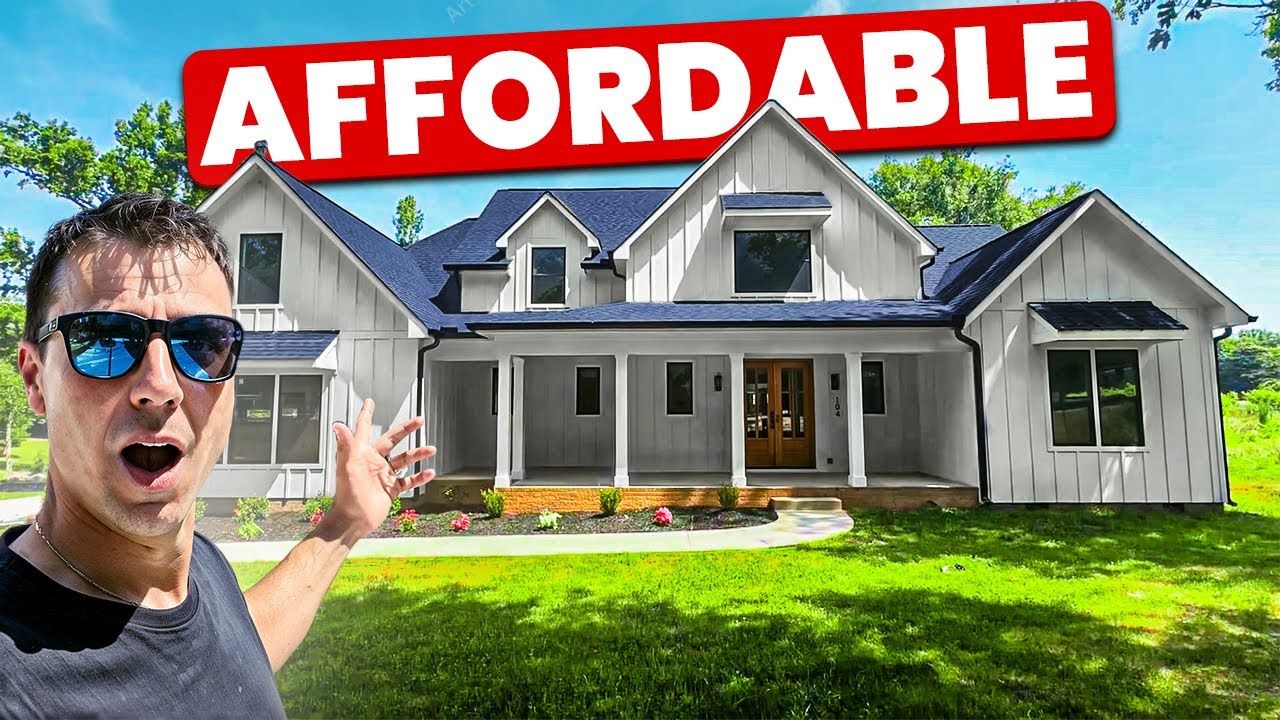 Man in sunglasses points towards a white farmhouse with 