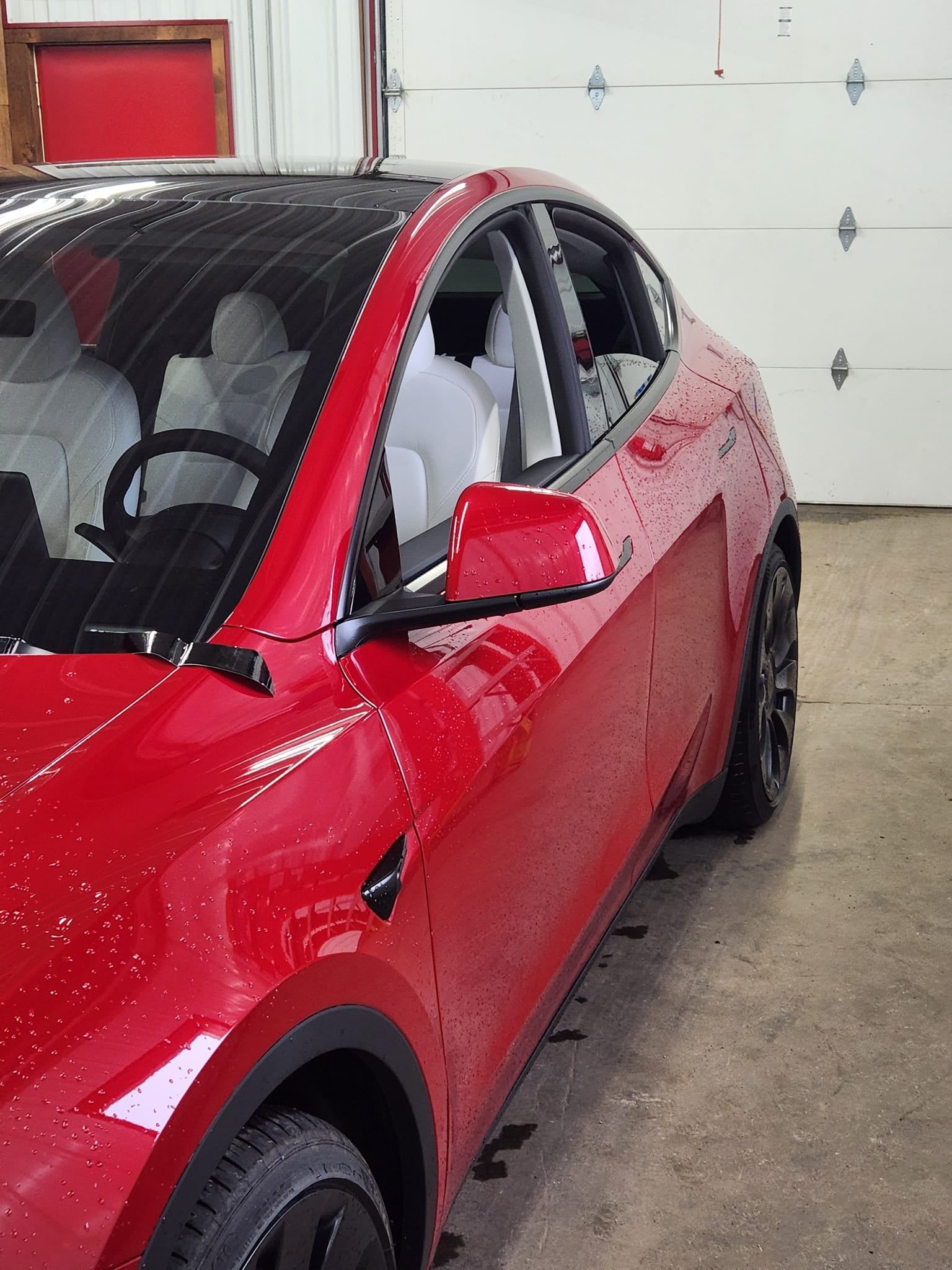 Red Tesla Model Y parked in a garage, showcasing its sleek design.