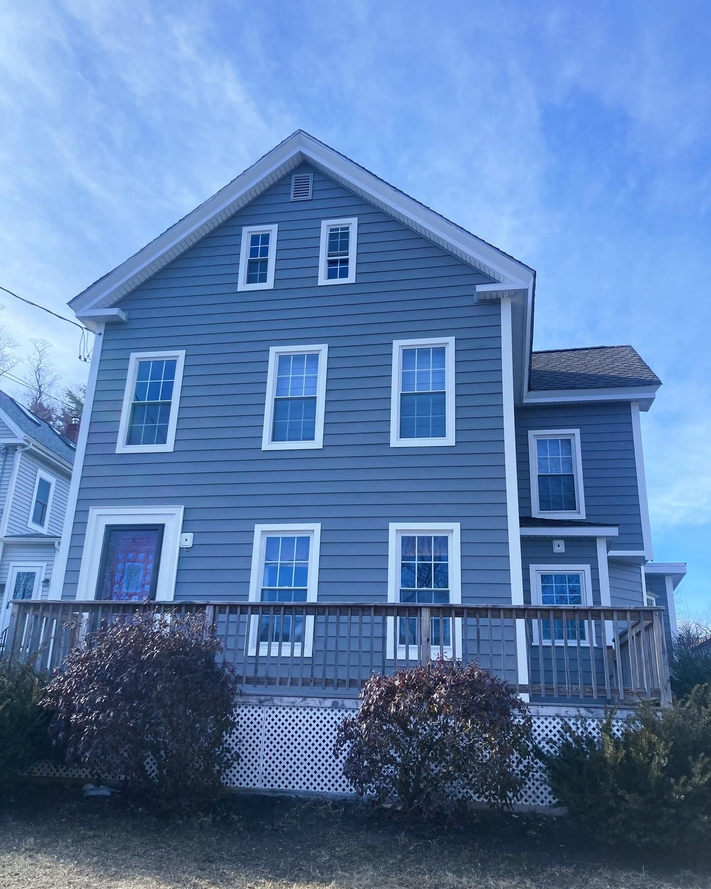 A large grey house with a blue sky in the background