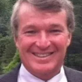 A man in a suit and tie is smiling for the camera.