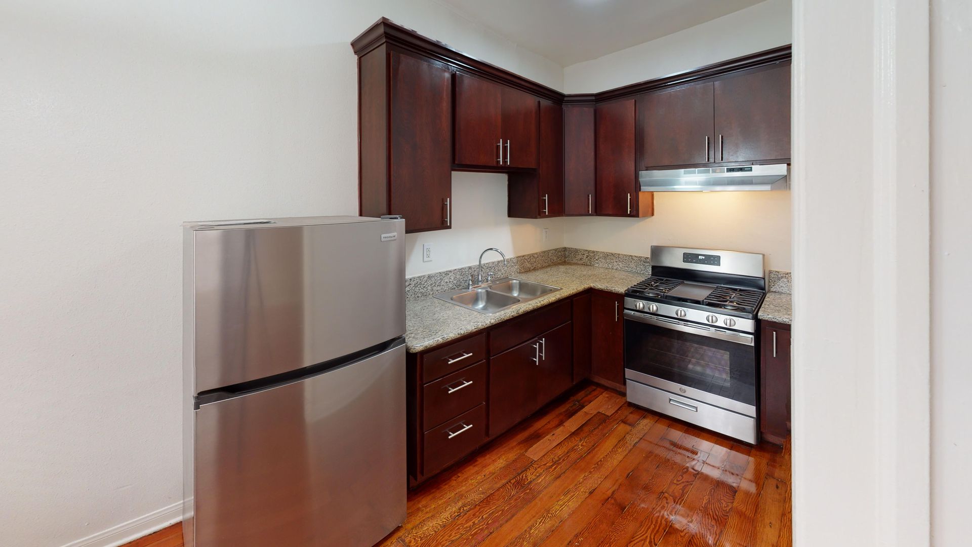 Kitchen with stainless steel appliances, dark wood cabinets, and granite countertops.
