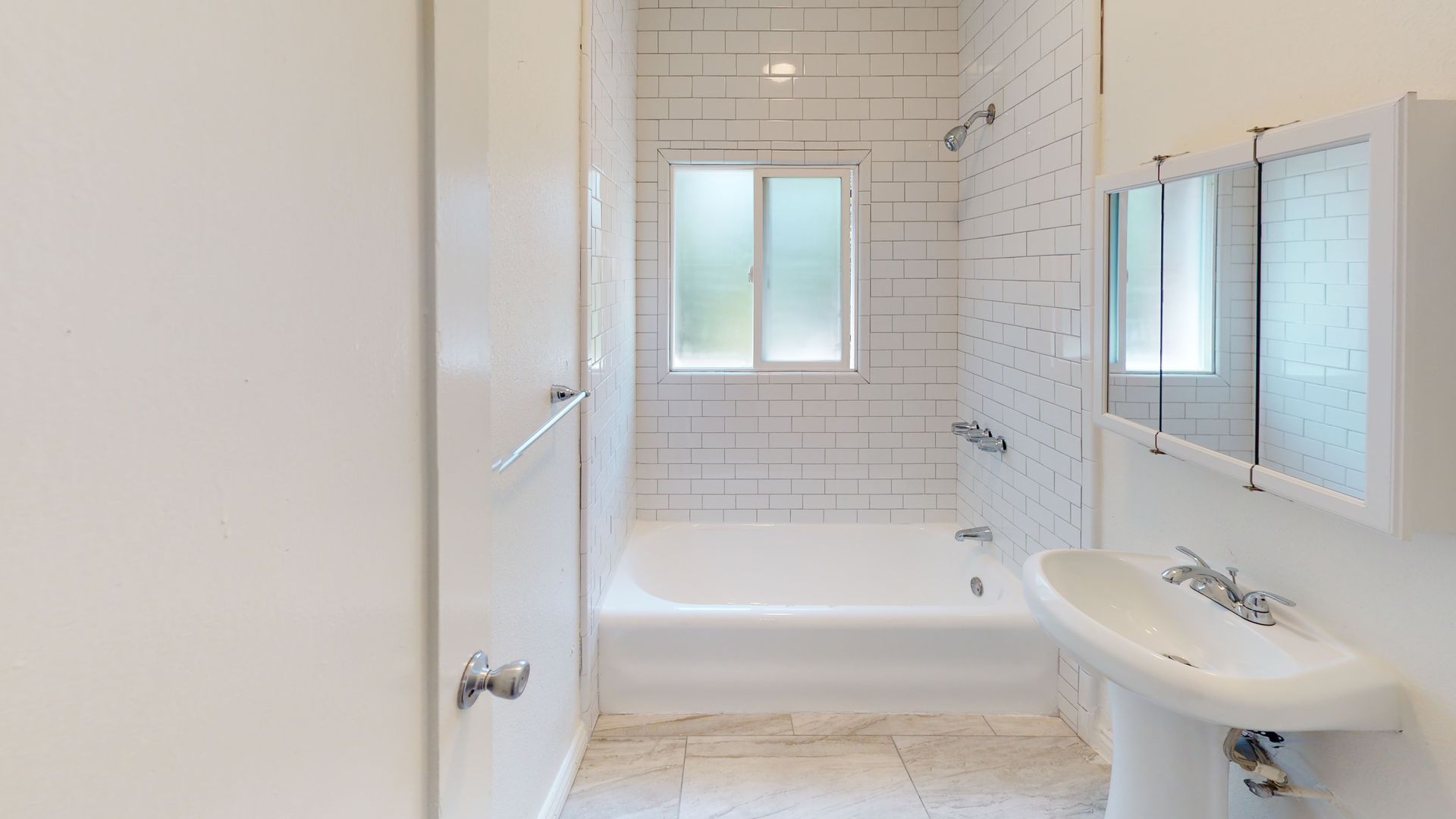 White bathroom with a tub, shower, sink, and window.