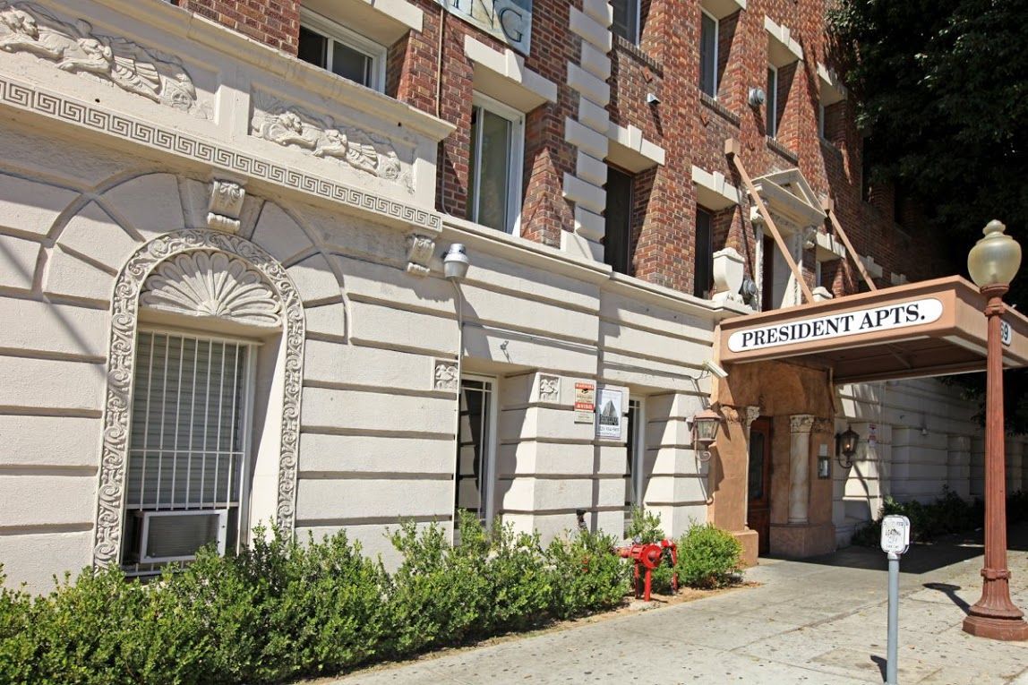 Apartment building facade with arched entrance, red brick, and ornate white trim. 