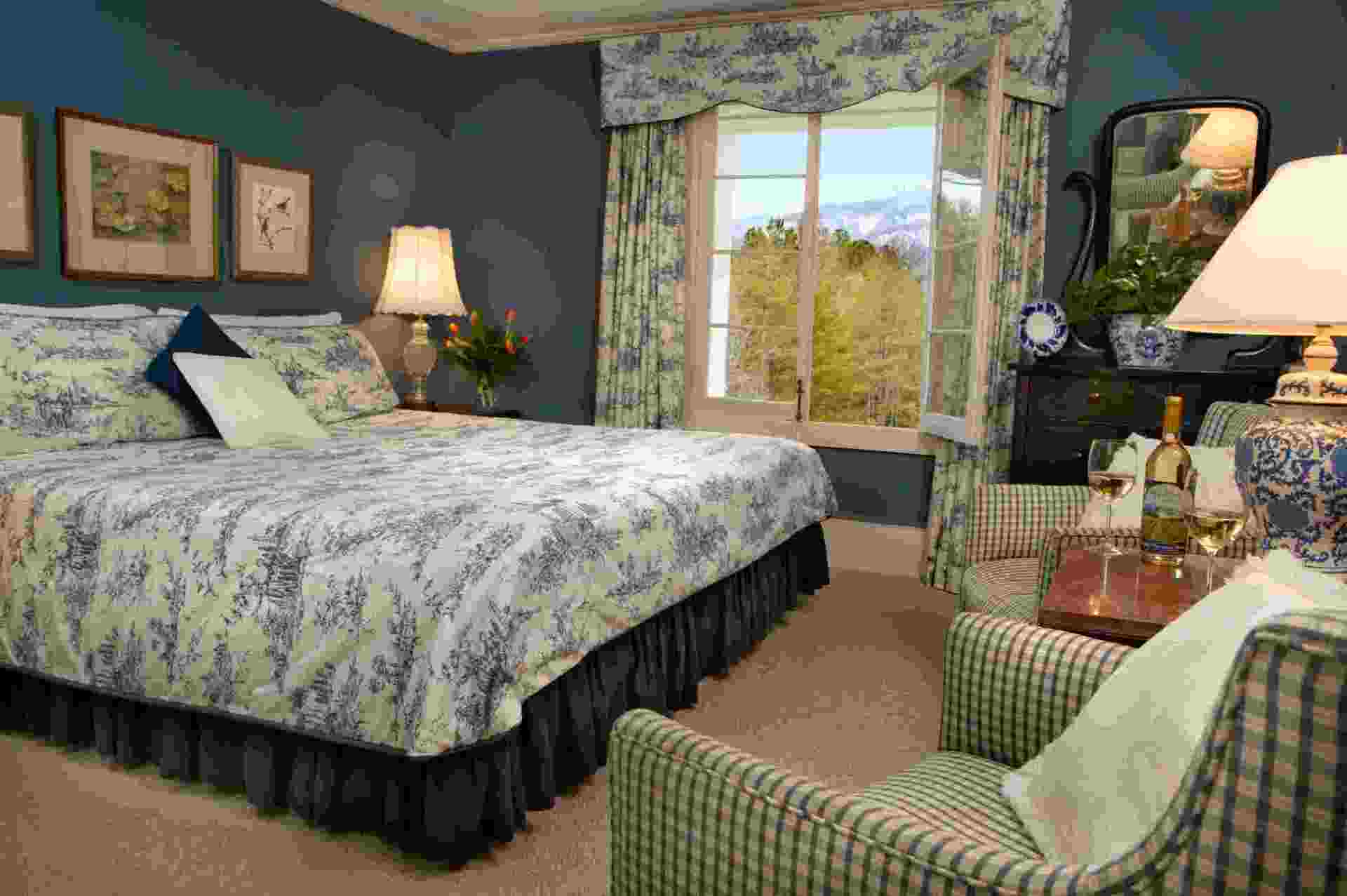 A bedroom with a king size bed , chairs , lamps and a window.