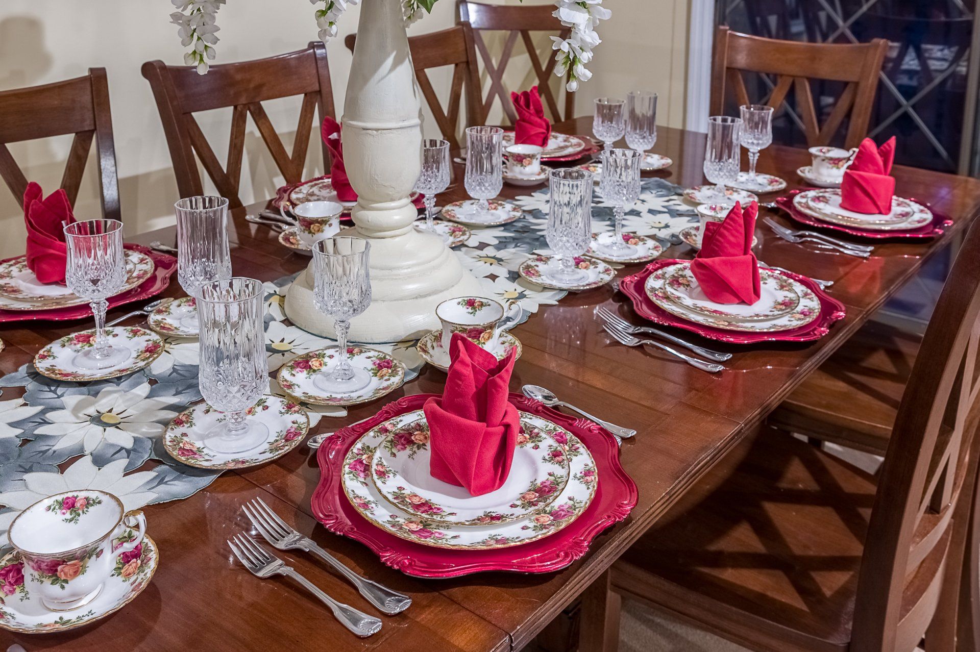 A dining room table is set with plates , glasses , and napkins.