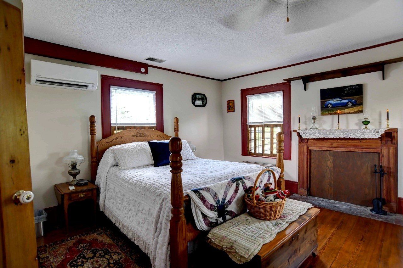 A bedroom with a bed , nightstand , fireplace and basket on the bench.