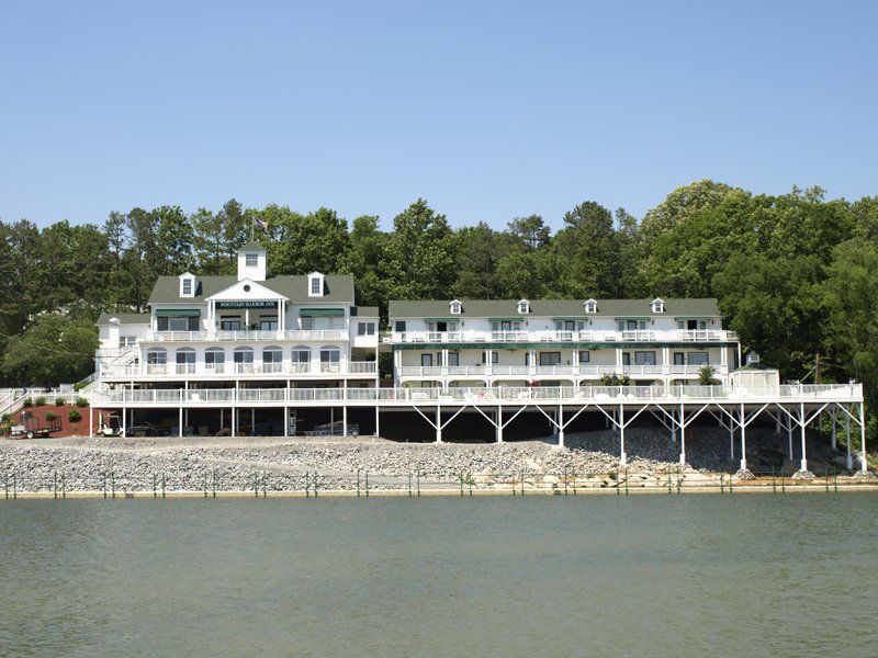 A large white house sits on the shore of a lake