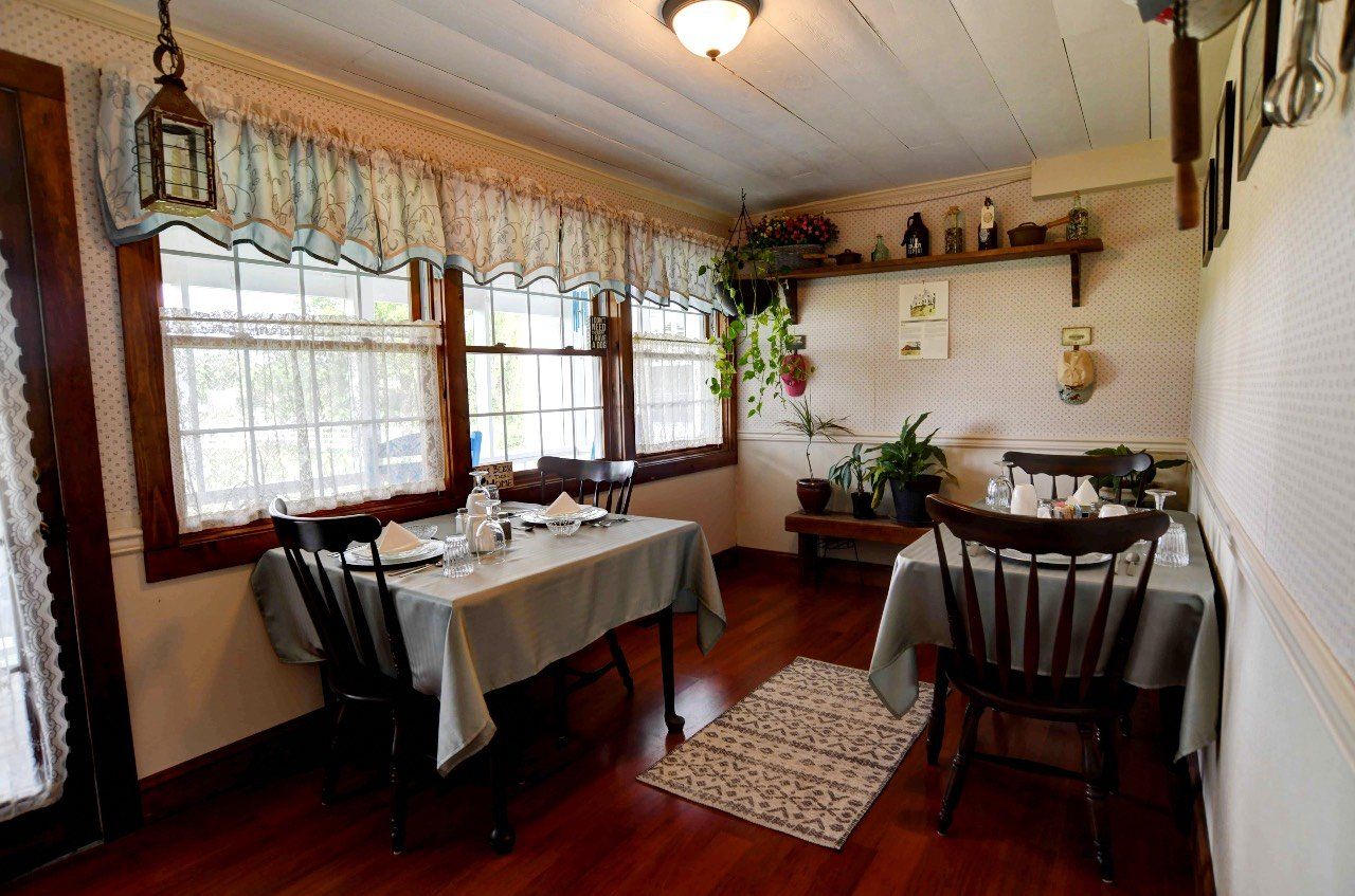 A dining room with tables and chairs and a rug on the floor.