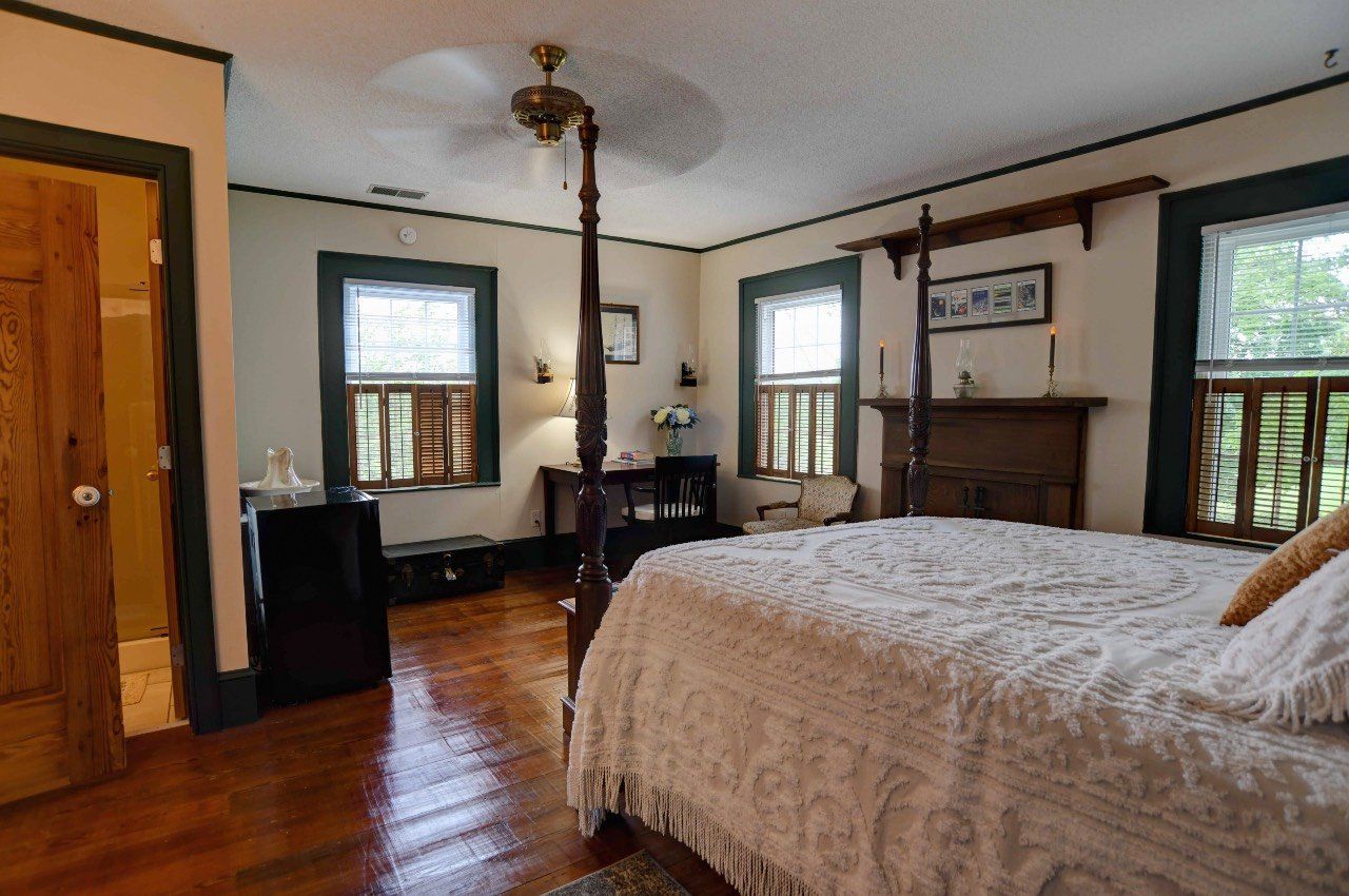 A bedroom with a four poster bed and a ceiling fan.