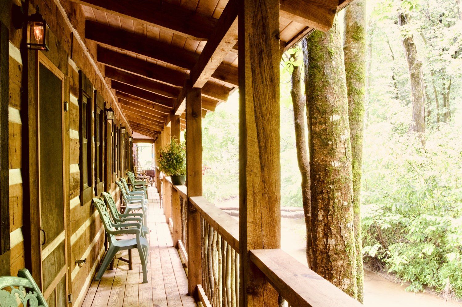 A long wooden porch with chairs and trees in the background