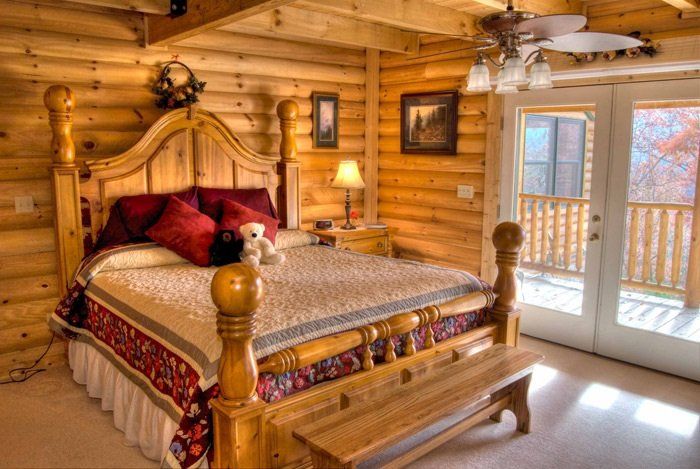 A bedroom in a log cabin with a king size bed and a bench.