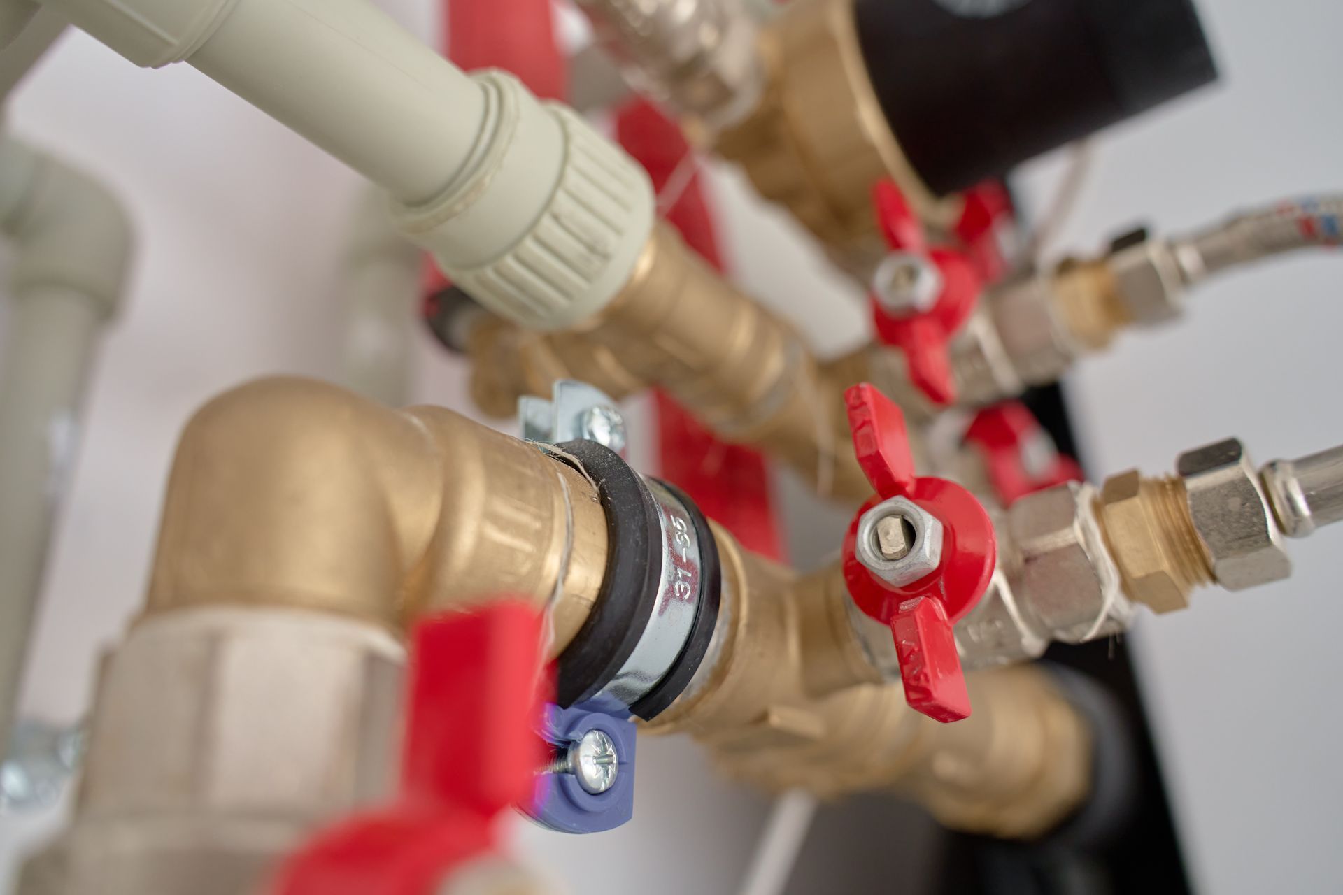 Close-up of brass plumbing pipes and red shutoff valves with fittings in a mechanical room