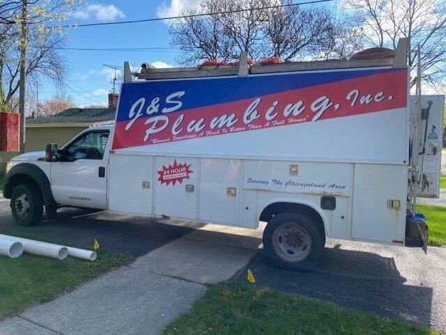 White J&S Plumbing truck parked on driveway, with company logo on the side.