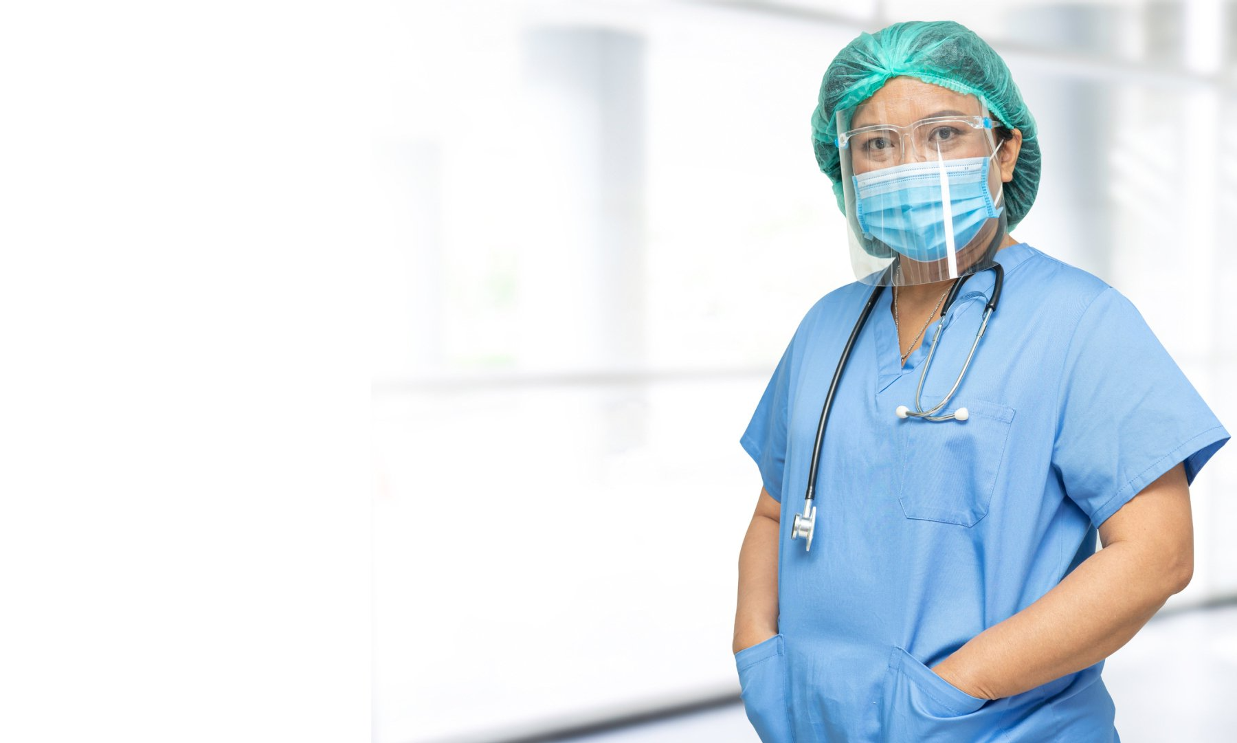 Una cirujana que lleva una máscara y un estetoscopio está de pie en un hospital.