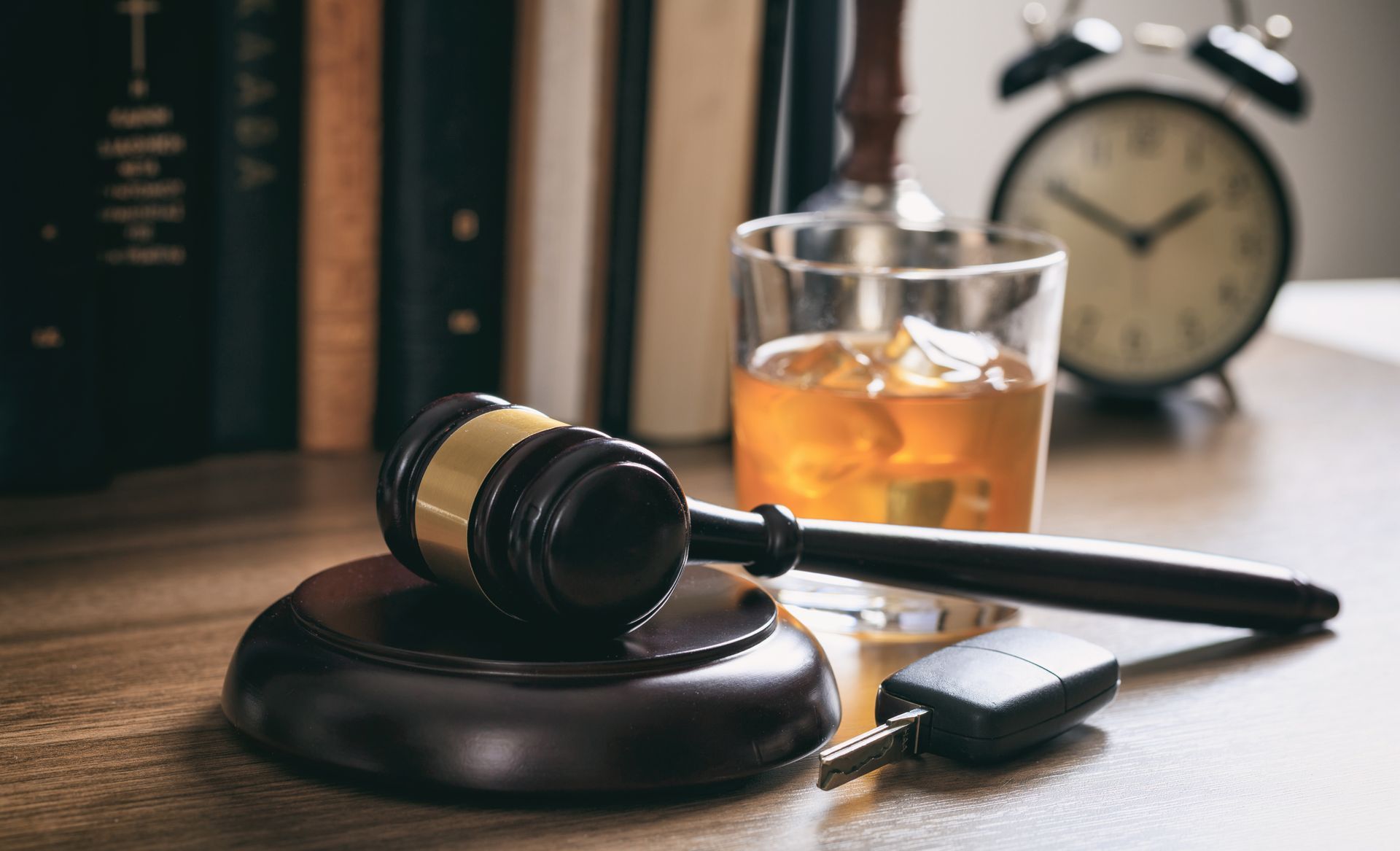 Law gavel, alcohol and car keys on a wooden desk.