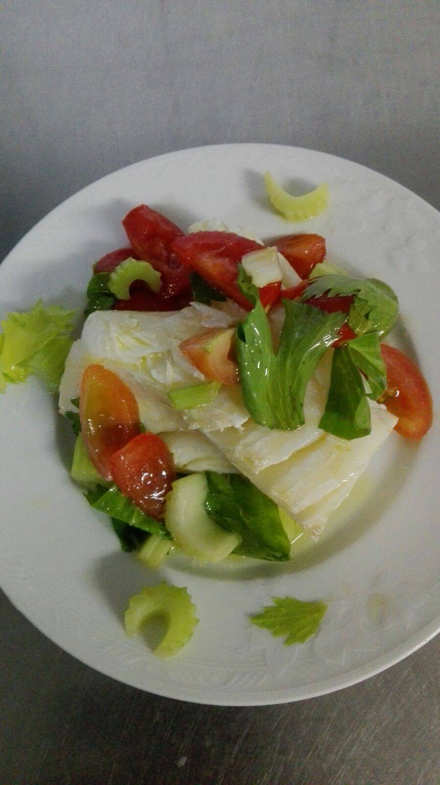 Insalata su un piatto bianco con pomodori, sedano e lattuga.