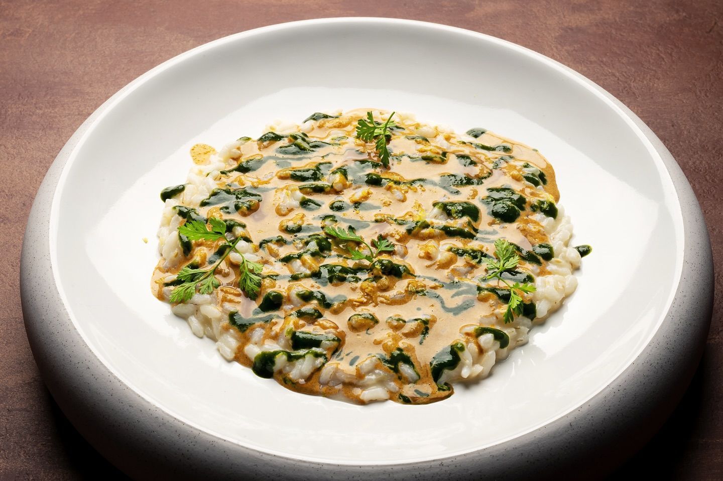 Risotto con spinaci e salsa su un piatto bianco.