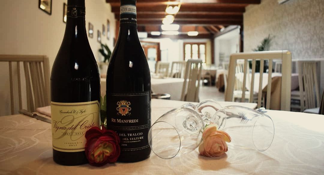 Due bottiglie di vino, due bicchieri e un fiore sul tavolo di un ristorante.