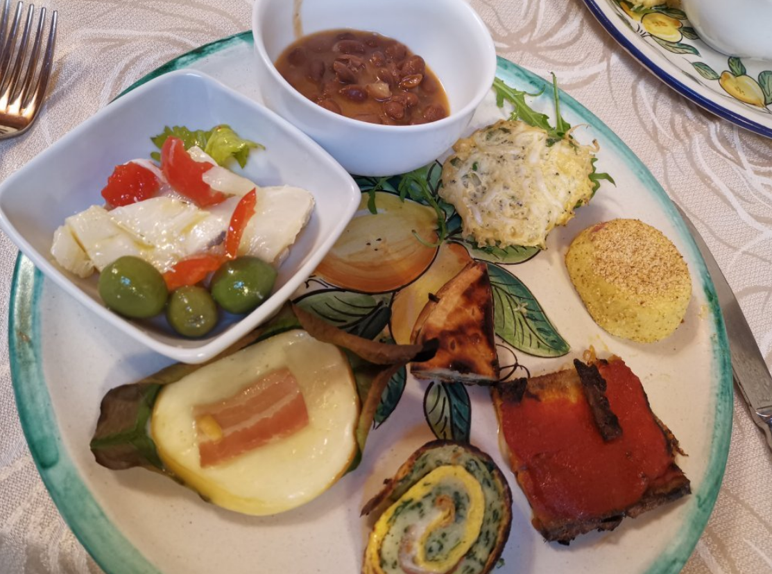 Piatto di antipasti italiani assortiti: formaggio, pomodori, olive, pane e salsa.