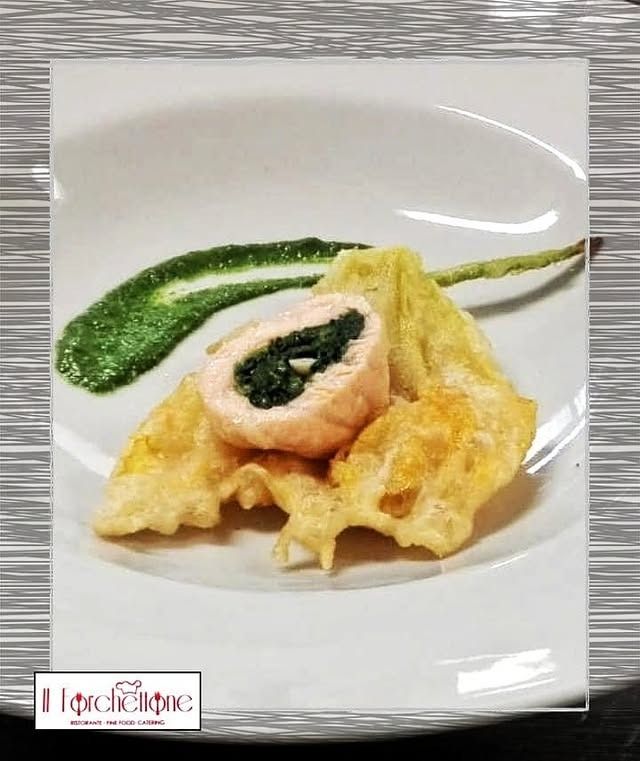 Rotolo di salmone con spinaci, verdure pastellate e salsa verde su un piatto bianco.