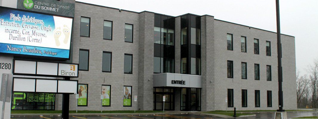 Vue extérieure d'un bâtiment moderne en briques avec des fenêtres, comportant une enseigne et une entrée marquée « Evolia ».