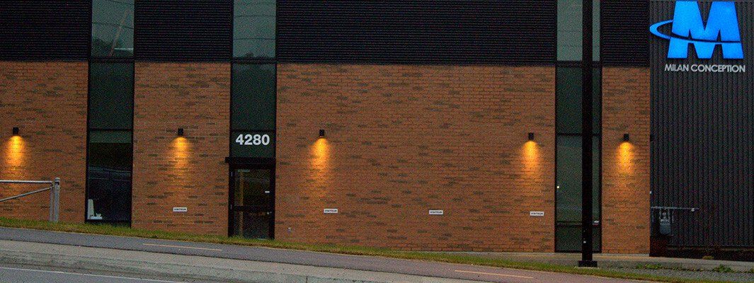 Extérieur d'un bâtiment en briques avec des fenêtres et une enseigne indiquant « JM Industries ».