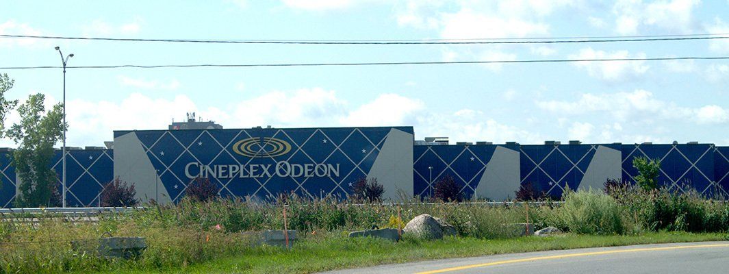 Bâtiment du cinéma Odeon avec un motif de losanges bleus sur la façade. Herbe verte et ciel bleu au premier plan.