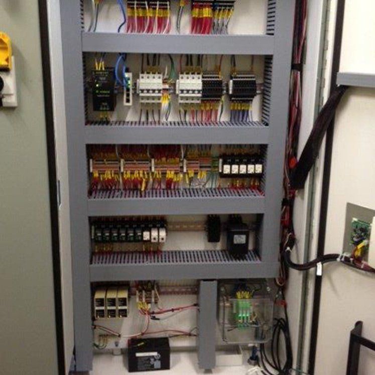 Panneau de commande avec divers composants électriques, des câbles et un boîtier en plastique transparent.