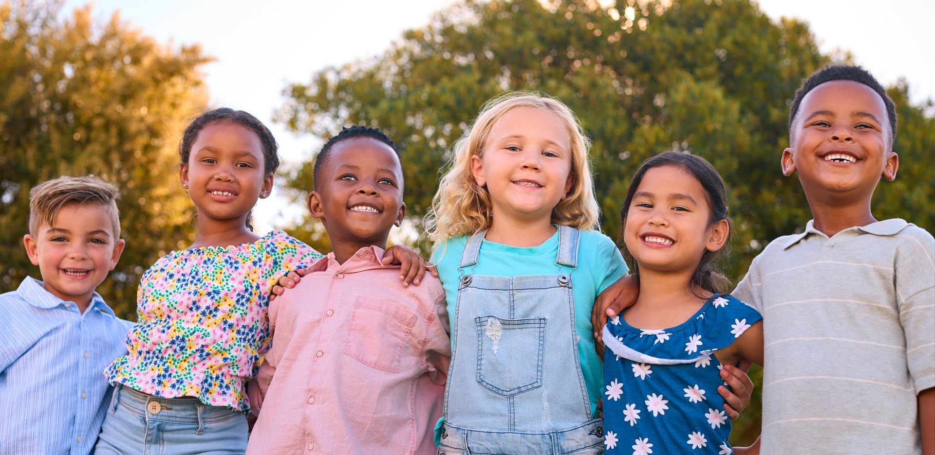 Group of diverse children smiling and embracing outdoors.