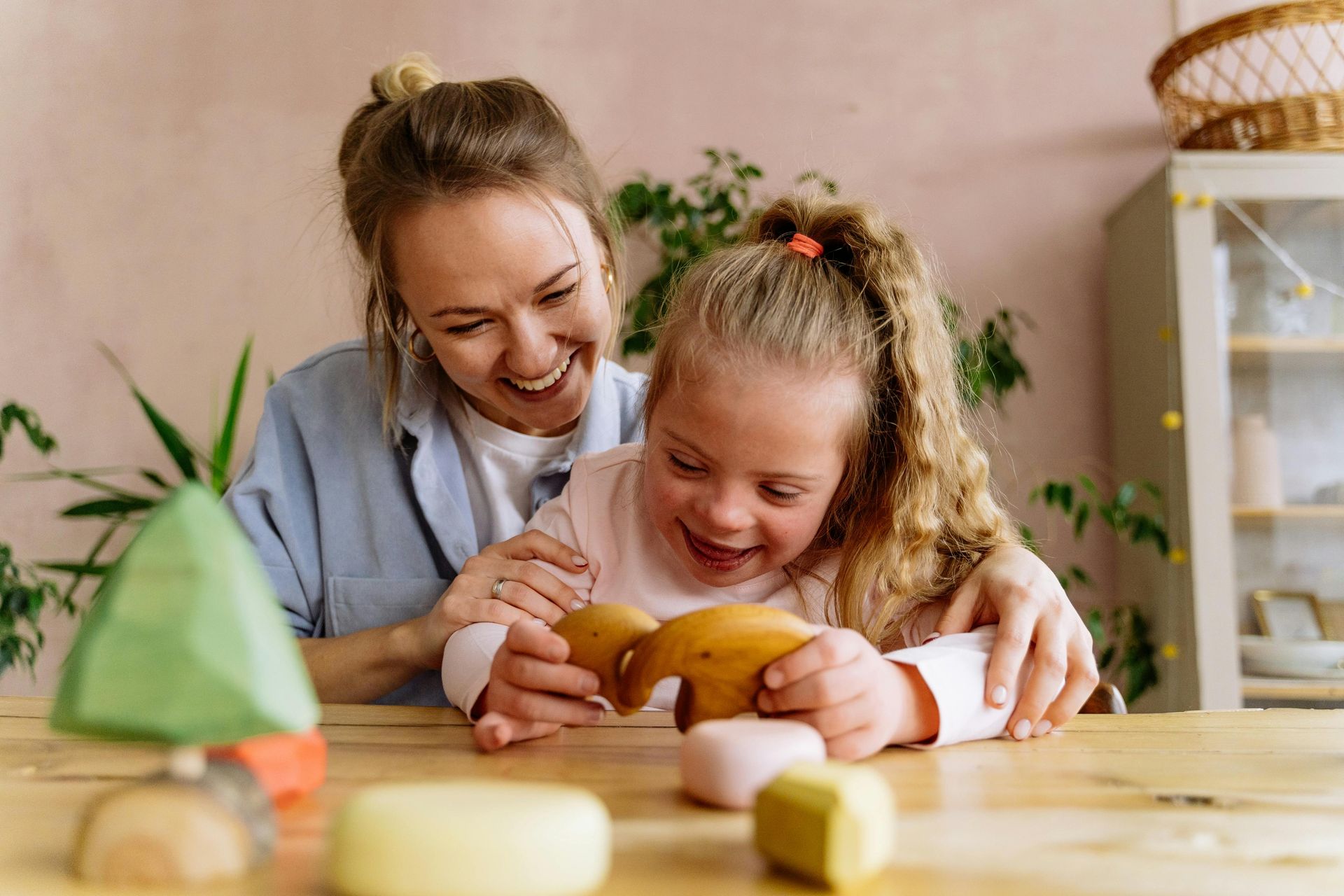 Woman holding and smiling at a laughing child, sitting near a cabinet.