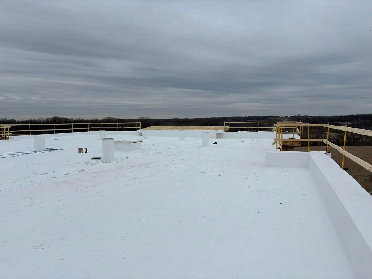 A white roof with a fence in the background on a cloudy day.