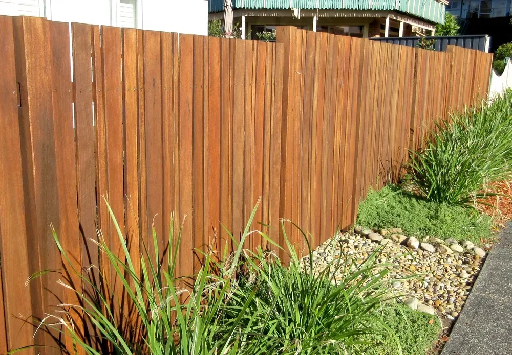 Wooden fence beside a gravel garden bed with green plants along a paved path — KLS Fencing In Tablelands, QLD