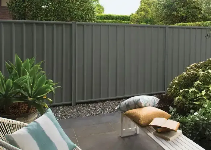 Backyard patio with gray fence, potted plants, and outdoor chair with cushions — KLS Fencing In Innisfail, QLD