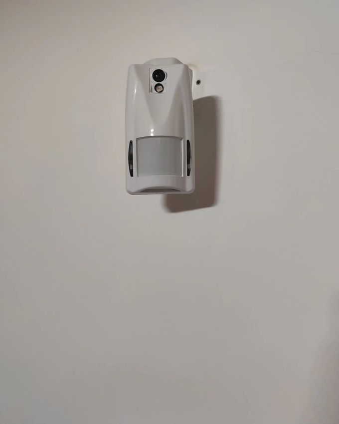 Sensore di movimento bianco fissato a una parete bianca.