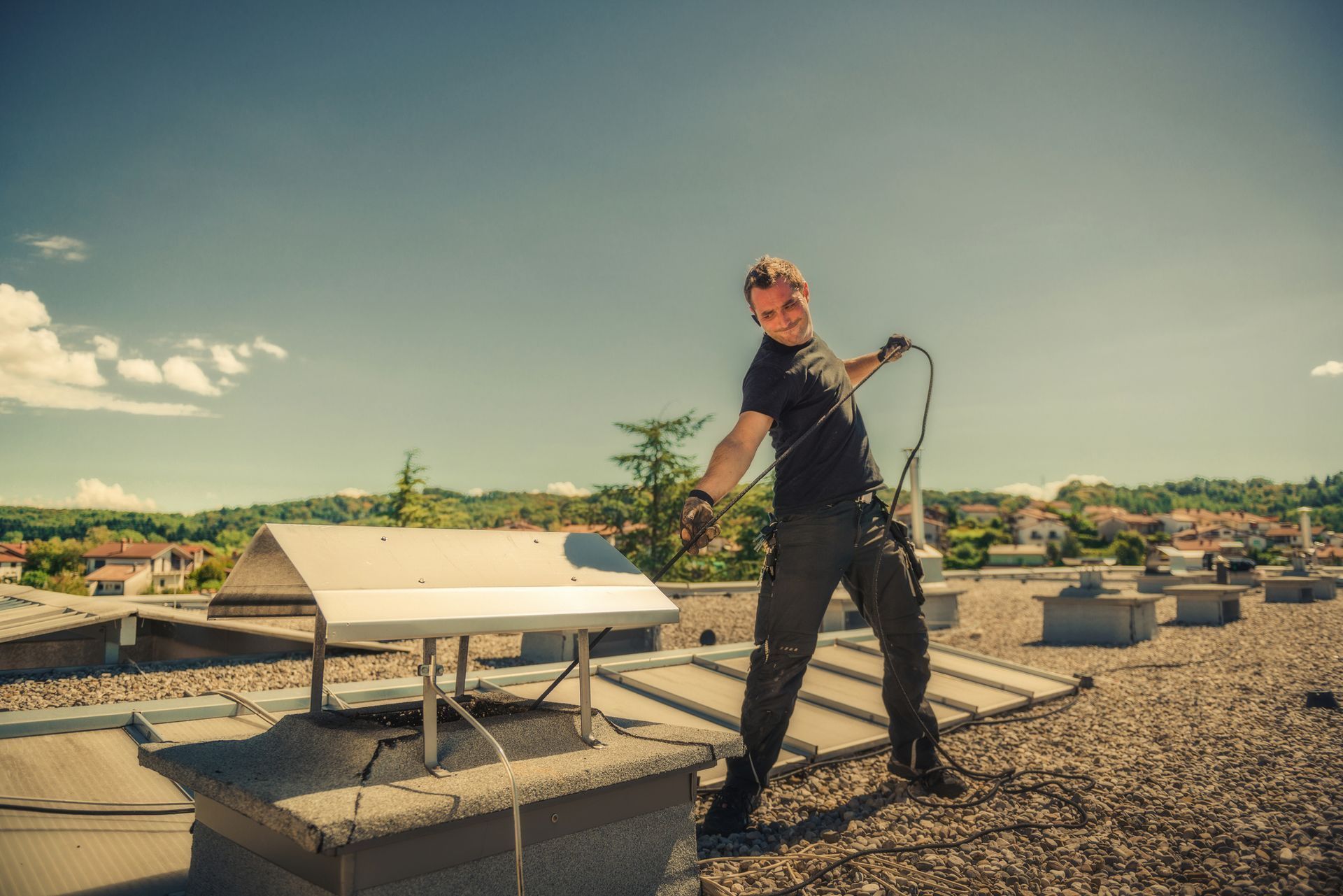 A man on a roof cleaning with a hose, demonstrating safe and effective chimney cleaning techniques.