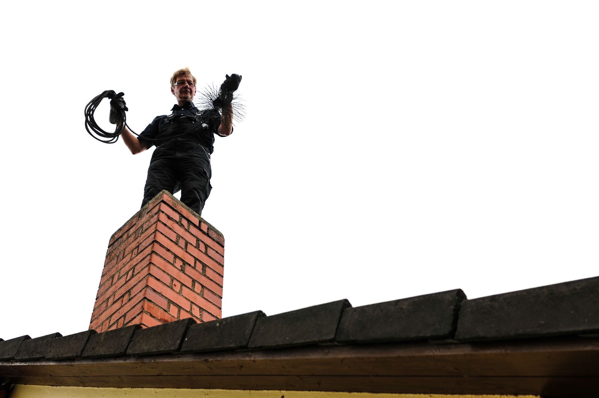 A chimney sweep stands on a brick chimney, holding tools against a white sky.