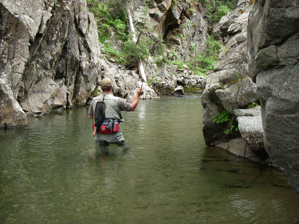 A man is standing in a river holding a fishing rod.