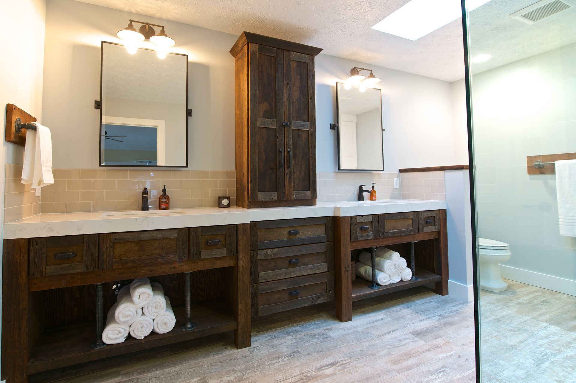 Rustic bathroom with wooden vanities, mirrors, and a glass shower.