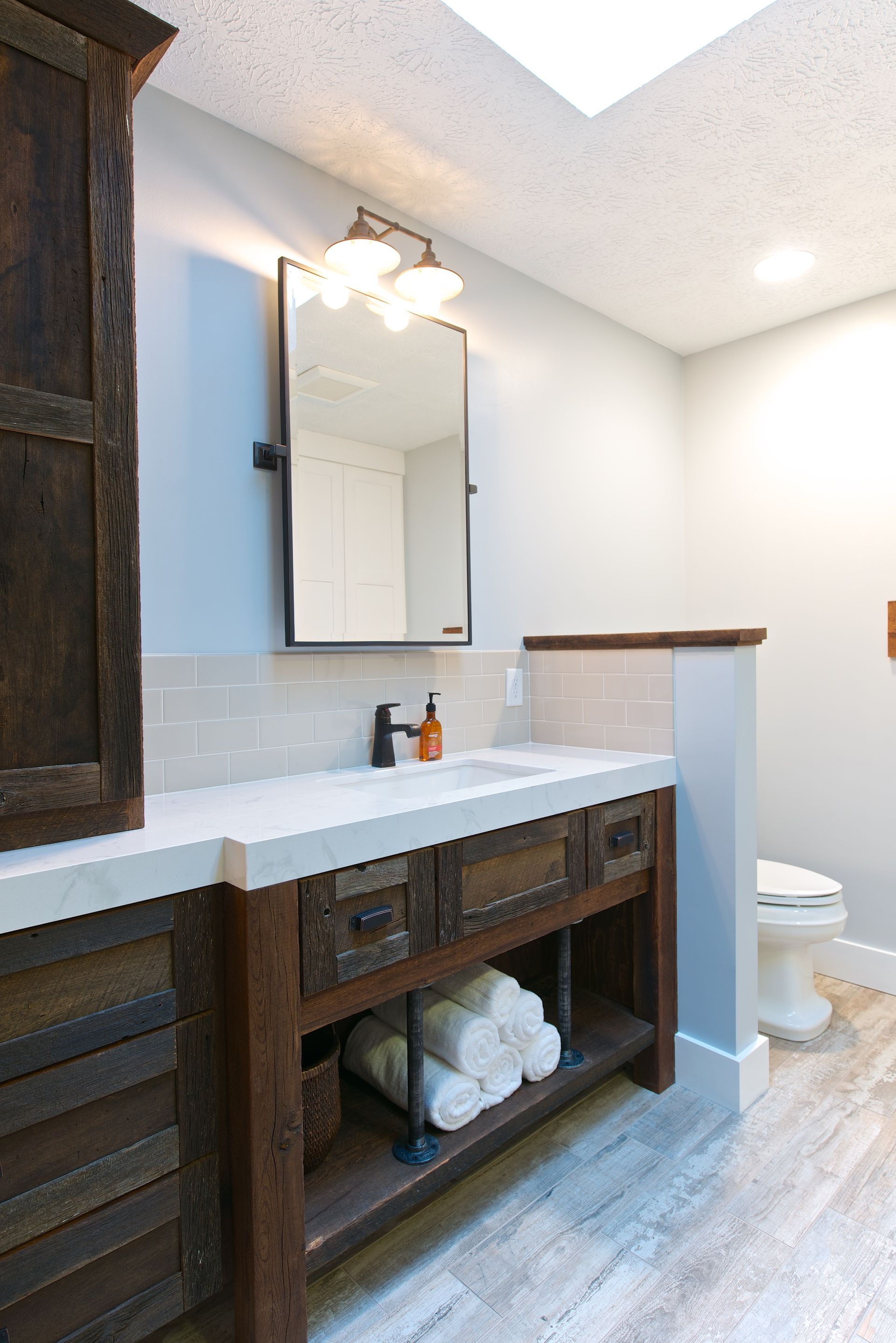 Rustic bathroom with wooden vanity, white countertop, and neutral walls.