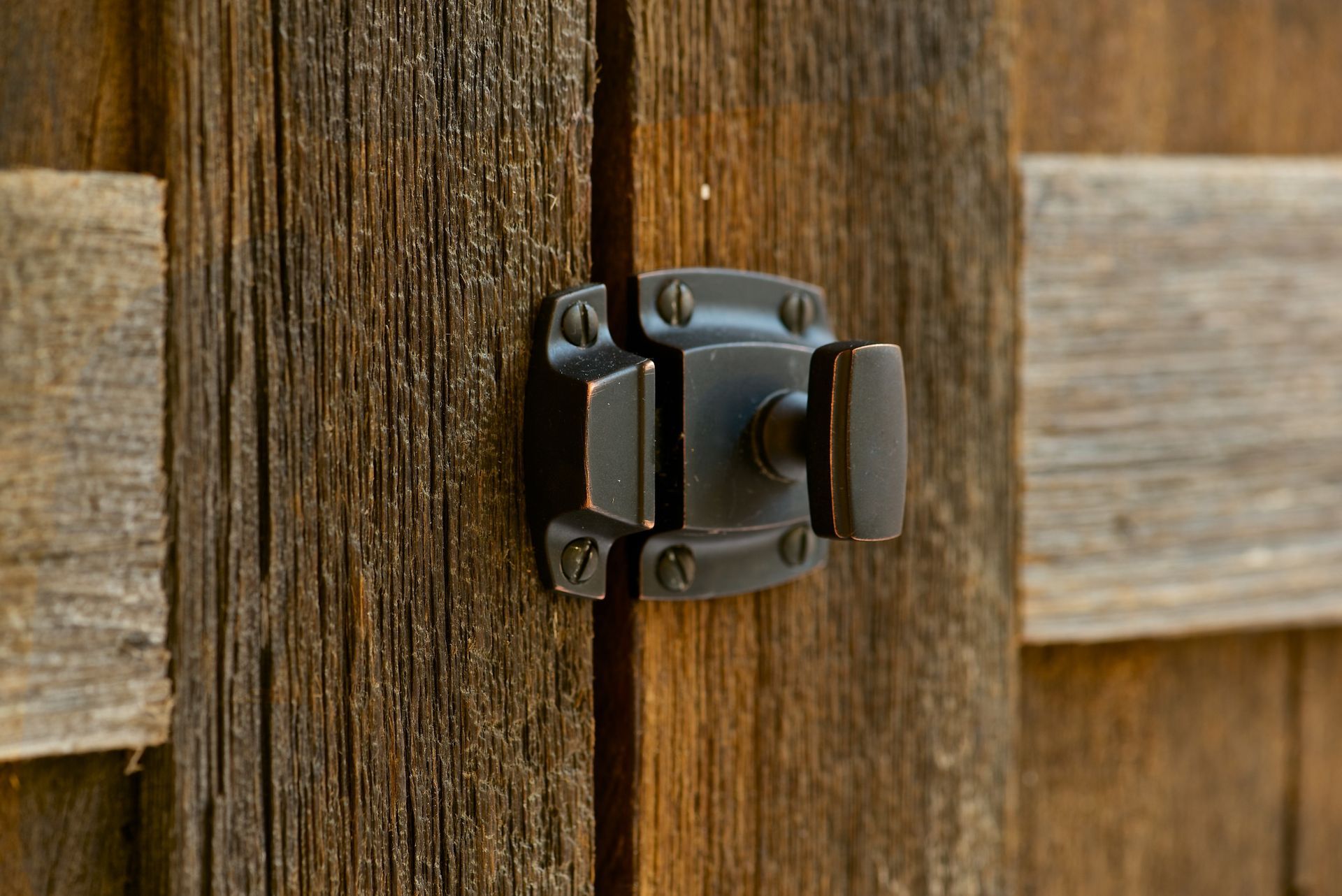 Bronze gate latch on weathered wooden planks.