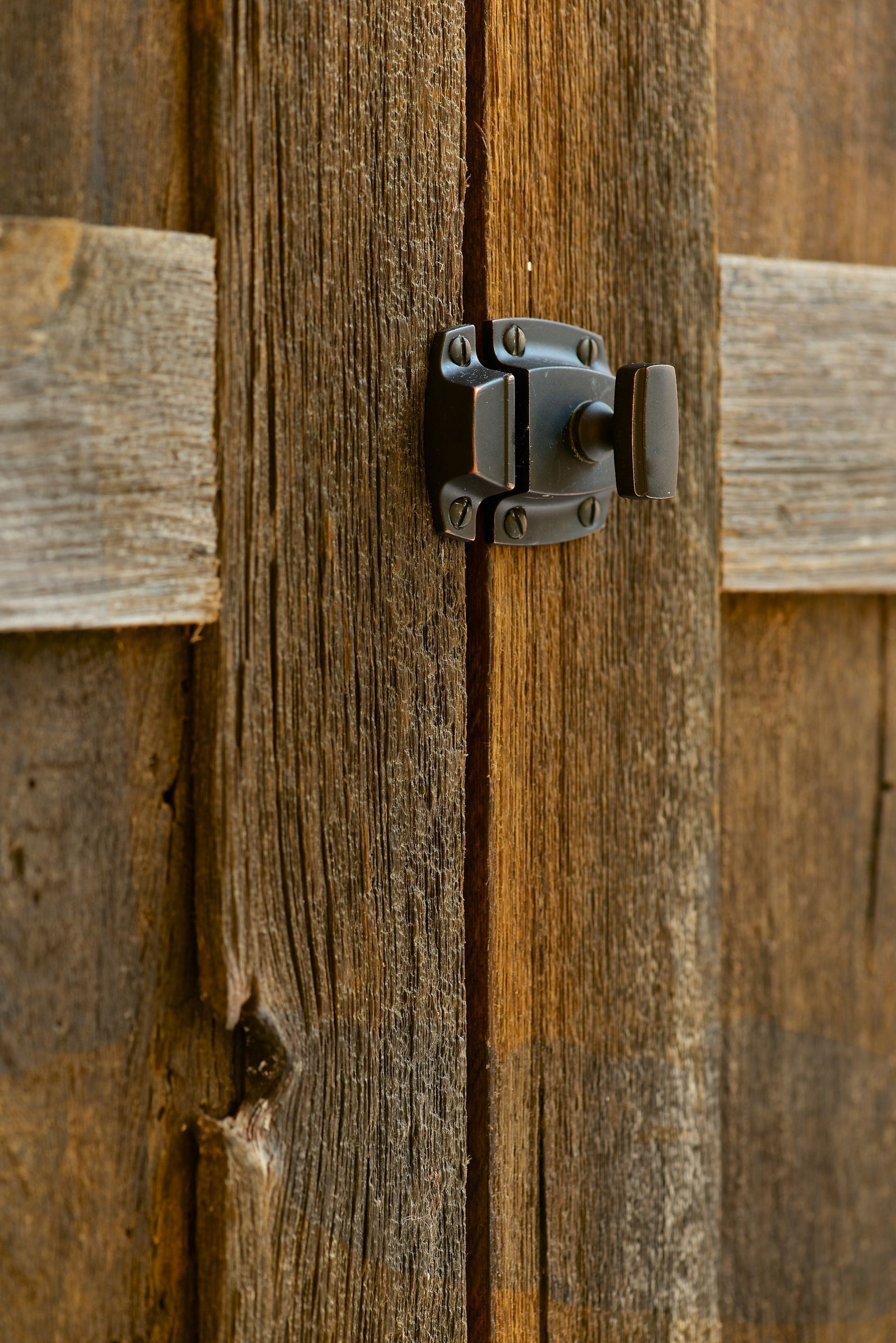 Metal latch on weathered wooden door.