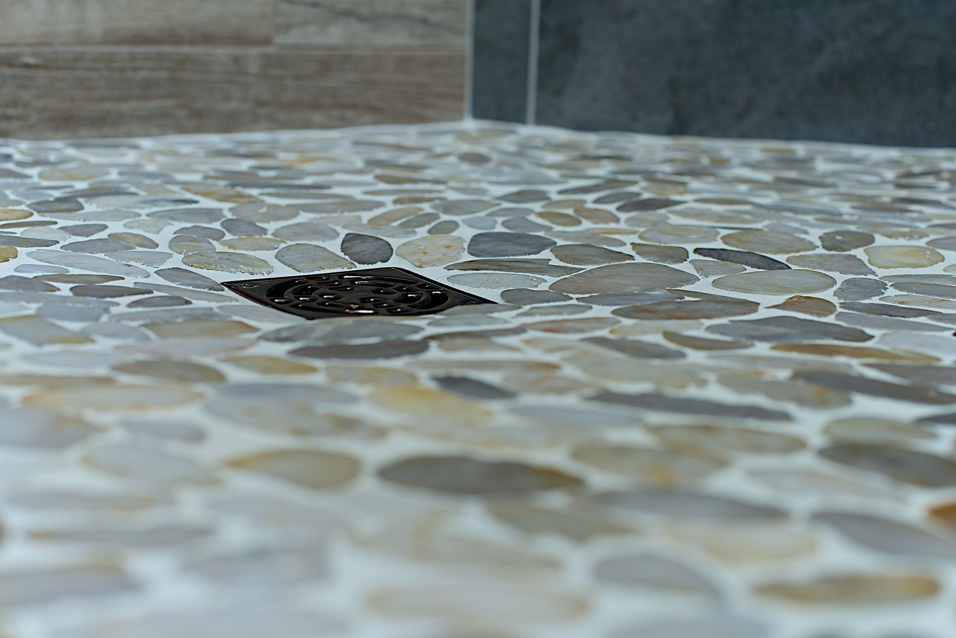 Shower floor with pebble tile surrounding a drain.