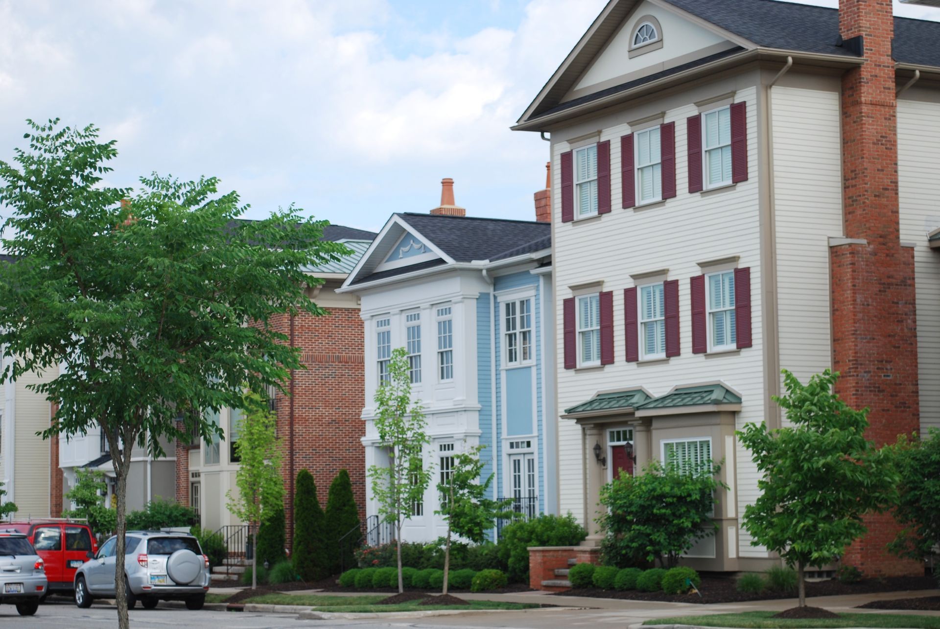 A row of houses with cars parked in front of them