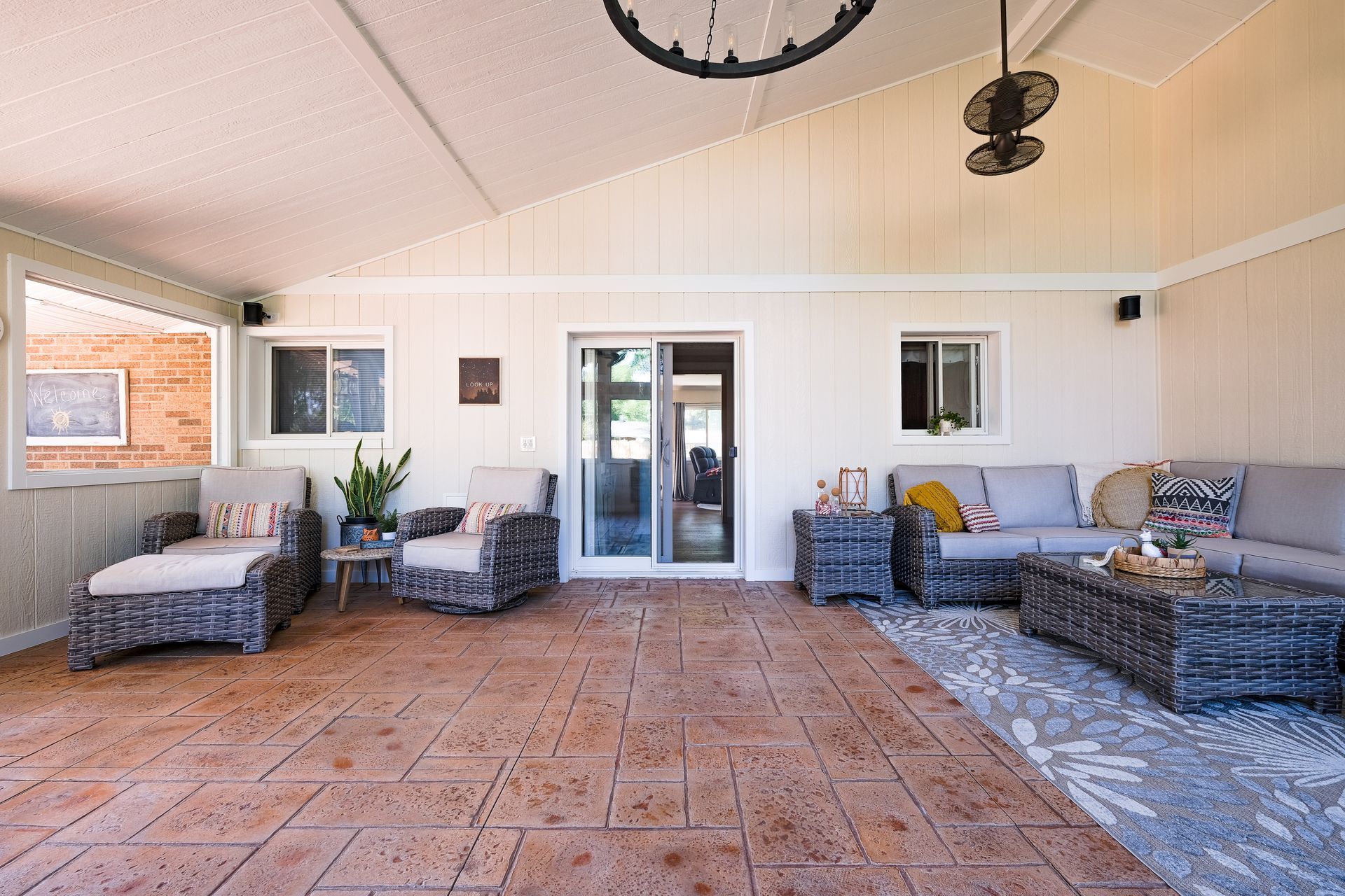 Covered patio with wicker furniture and a patterned rug.