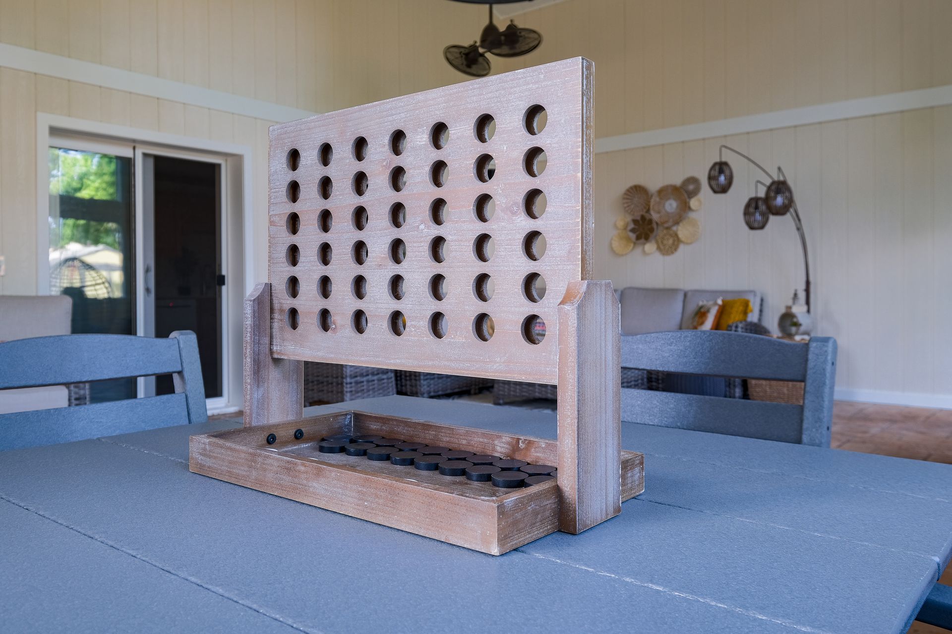 Giant wooden Connect Four game on a gray table, outdoors.