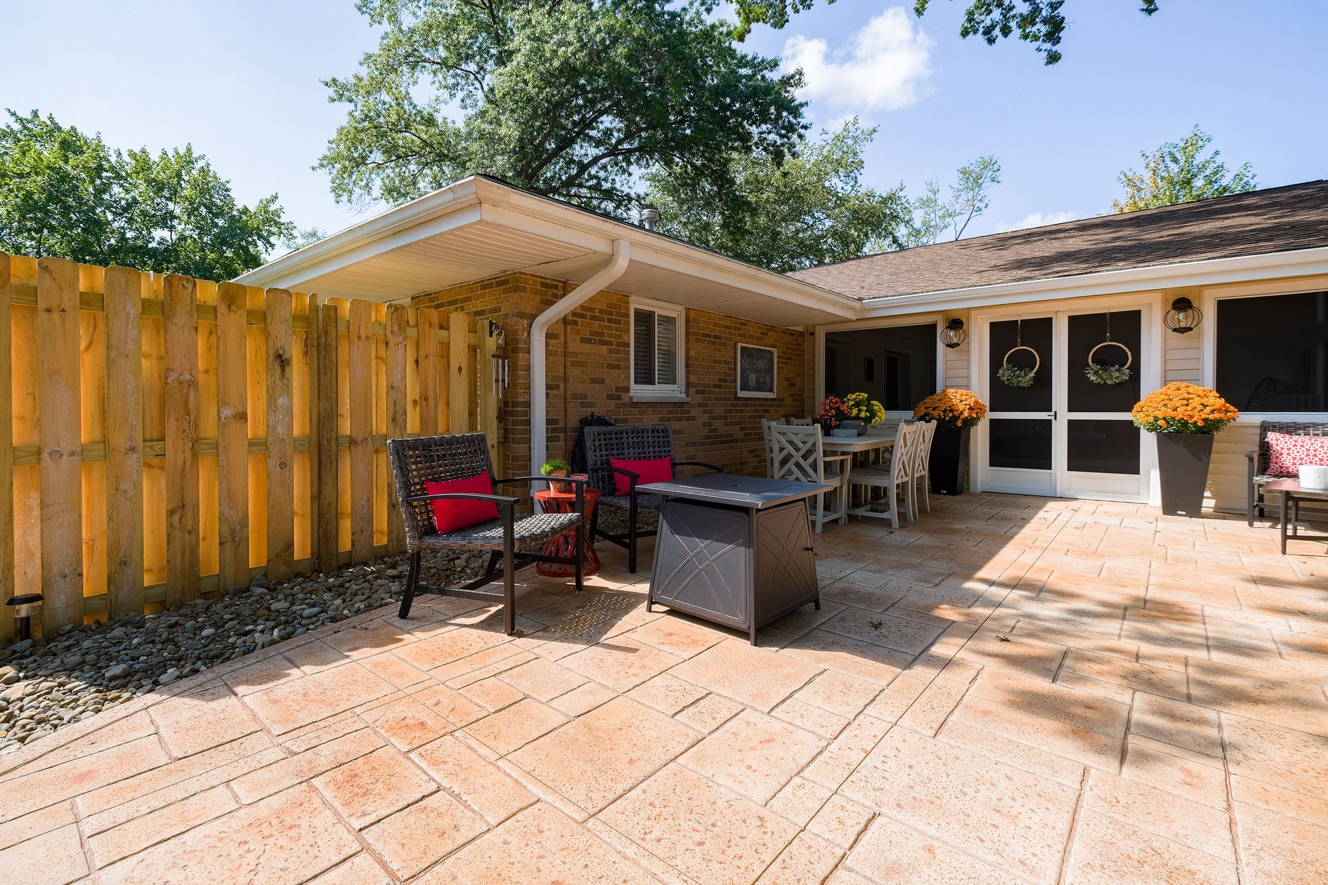 Patio with seating, dining table, and brick house under a blue sky.