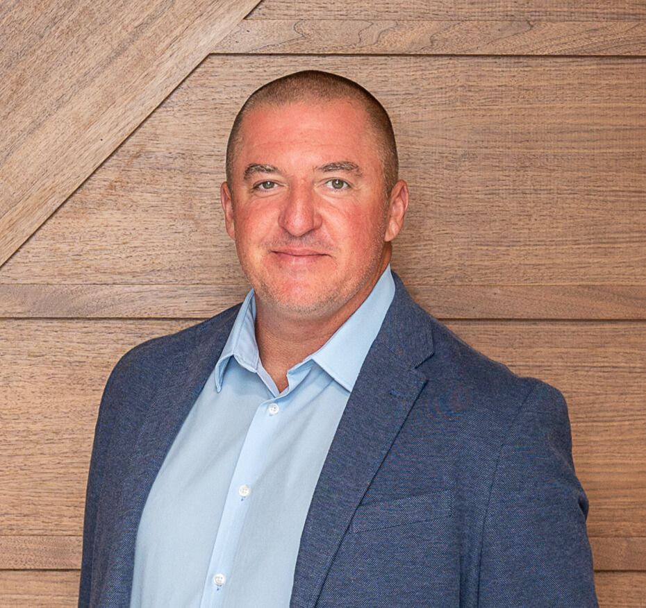 Woman with glasses, smiling, in a dark turtleneck and red jacket.