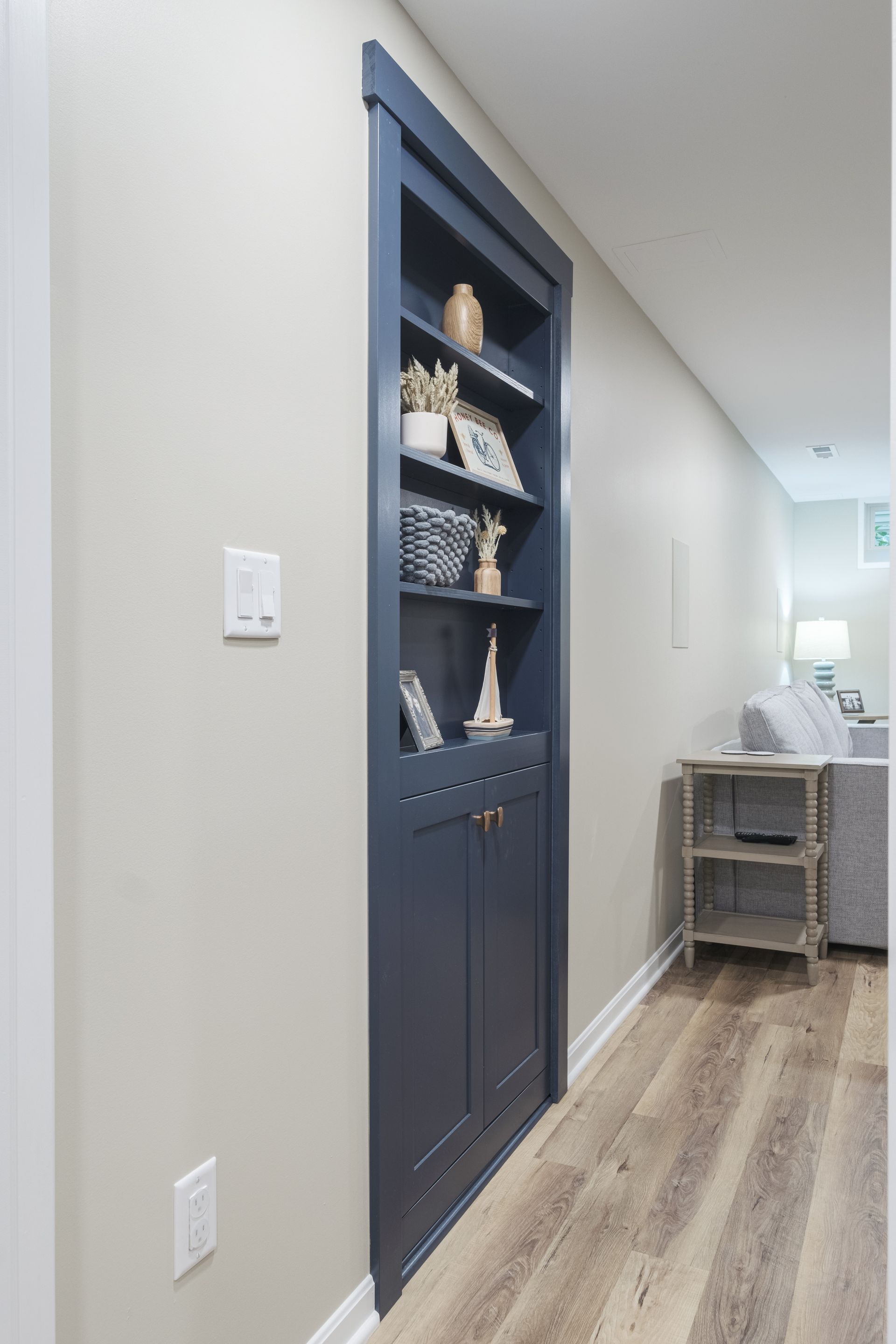 A hallway with a built in bookshelf and a couch.